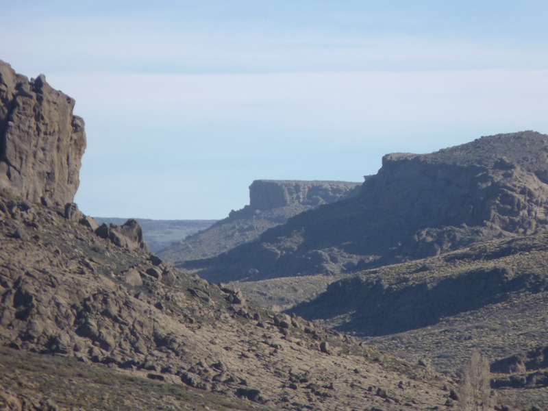 Jinete cruzando cañadón bajo cielo tormentoso